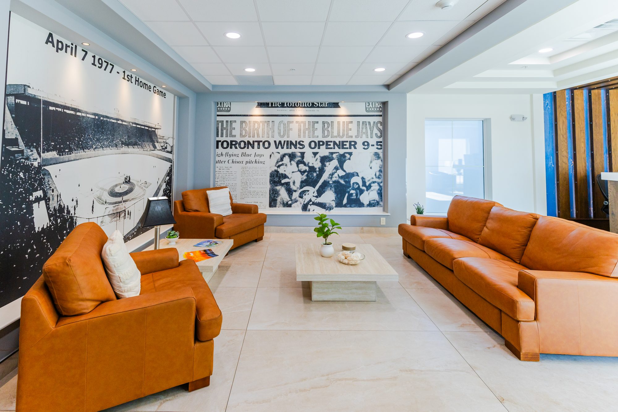 Lounge with leather sofas and a wall-sized mural of ballpark history