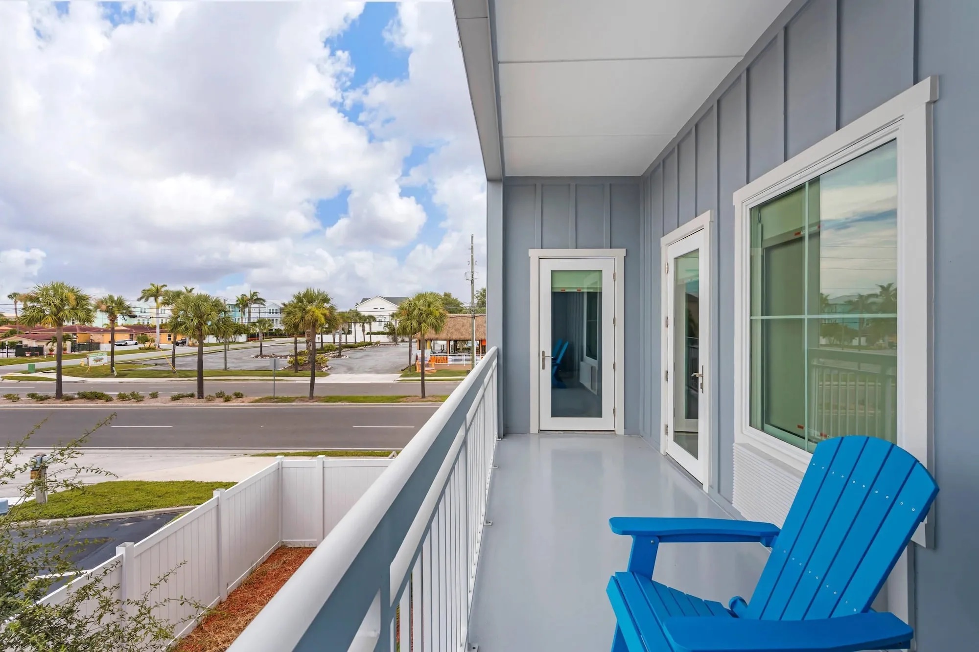 Balcony with a blue Adirondack chair overlooking palms